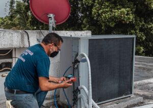 HVAC technician repairing an outdoor air conditioner unit with manifold gauges